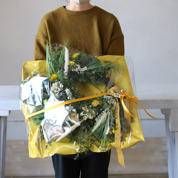 大きいフラワーリースを持っている人